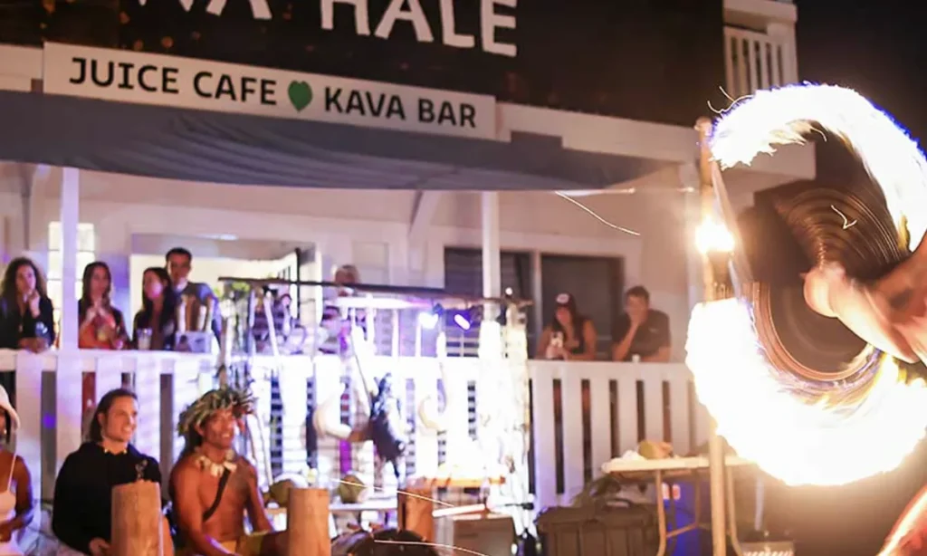 Fire knife dancer performing outside Awa Hale juice cafe and kava bar in Kapa'a as a crowd watches from the porch