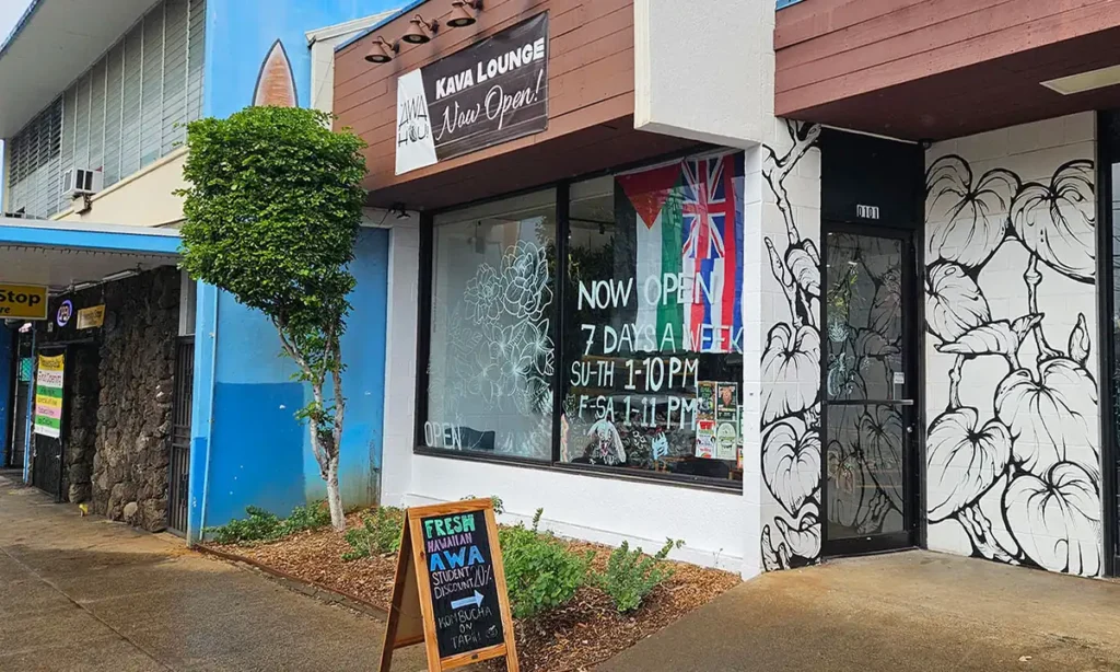 Storefront of 'Awa Hou! Kava Lounge in Honolulu with a black and white kava leaf mural and a chalkboard sign outside