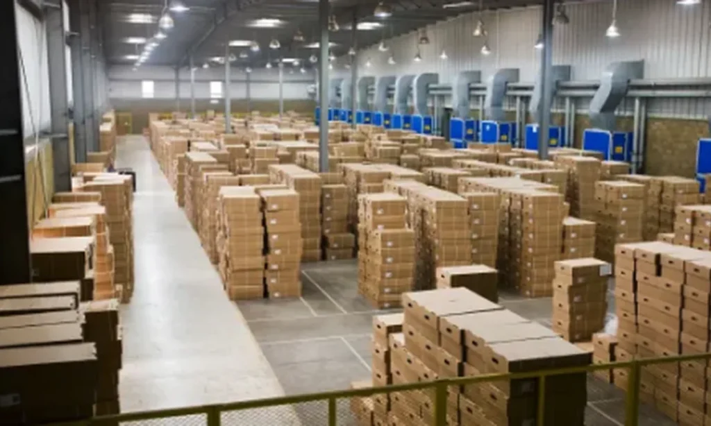 Warehouse interior with rows of stacked cardboard boxes on pallets under industrial lighting
