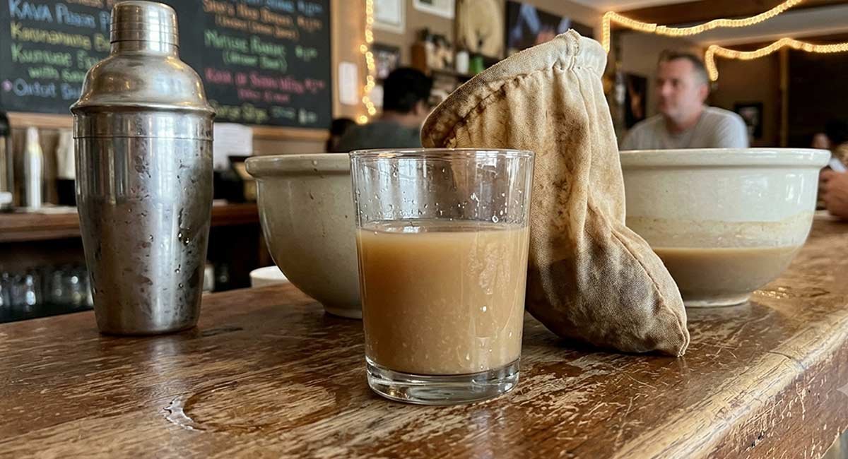 Alternate angle of modern kava bar preparation with a shaker and strainer bag