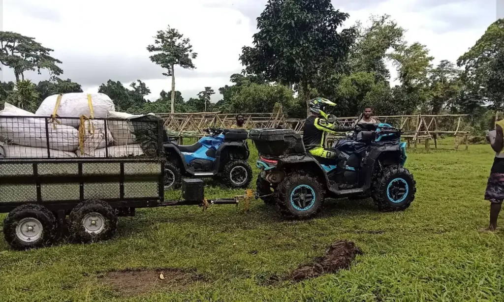 ATVs pulling a trailer loaded with sacks of kava at a Pacific Santo Ltd farm site